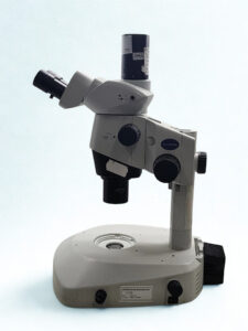 Side View - Olympus SZX10 Research Stereo Microscope Side profile of the Olympus SZX10 Stereo Zoom Microscope mounted on a high-clearance stand with transmitted light base and camera attachment.