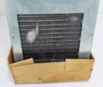 Close-up view of the rear aluminum fins and condenser coil assembly on an nVent HOFFMAN G521246G050 narrow-profile industrial climate control unit sitting in its shipping base.