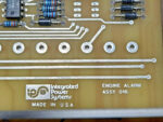 Integrated Power Systems logo etched on an engine alarm module circuit assembly made in the USA with visible copper traces and resistors.