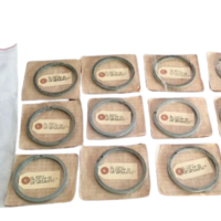 Lot of 15 new surplus Micarta piston rings part number 269-312232-999 for 3-1/2 inch bore industrial compressors, displayed on cardboard backing next to their original protective plastic packaging.